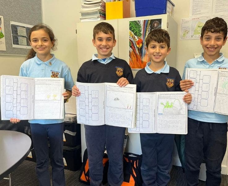 Four BLSPS Students smiling and displaying their book work