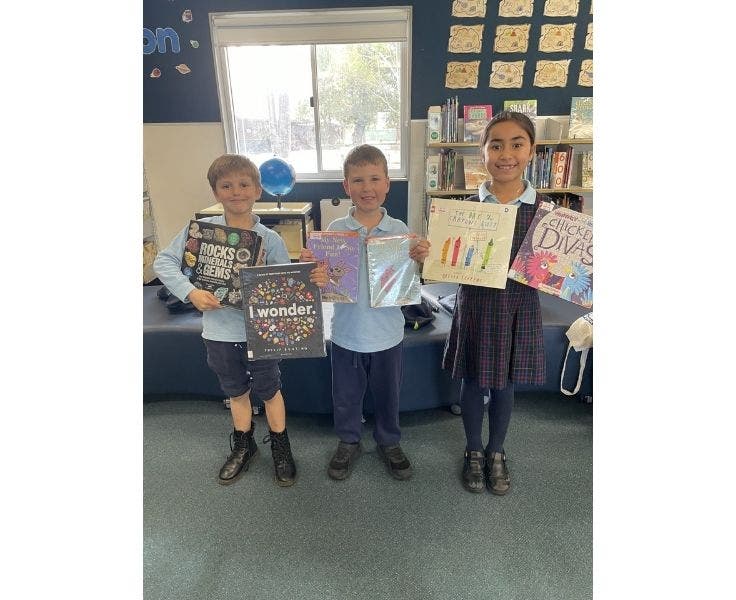 BLSPS Library with three children displaying books